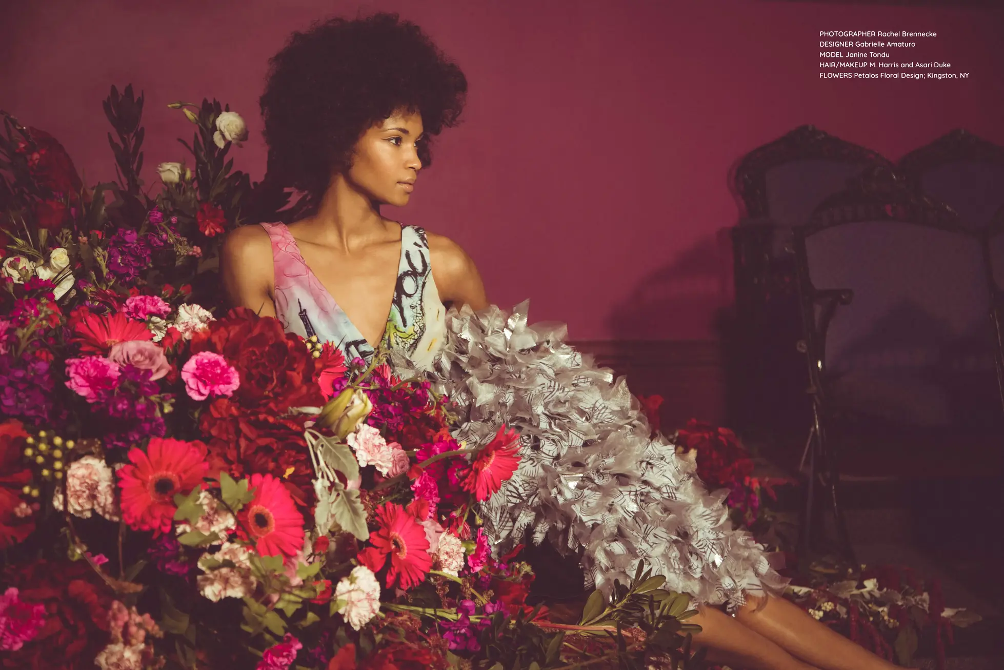 Editorial fashion photograph from Marist College Senior Thesis collection featuring a dramatic dress design with pink gradient and zebra print elements, surrounded by vibrant red and pink floral arrangements against a deep burgundy backdrop